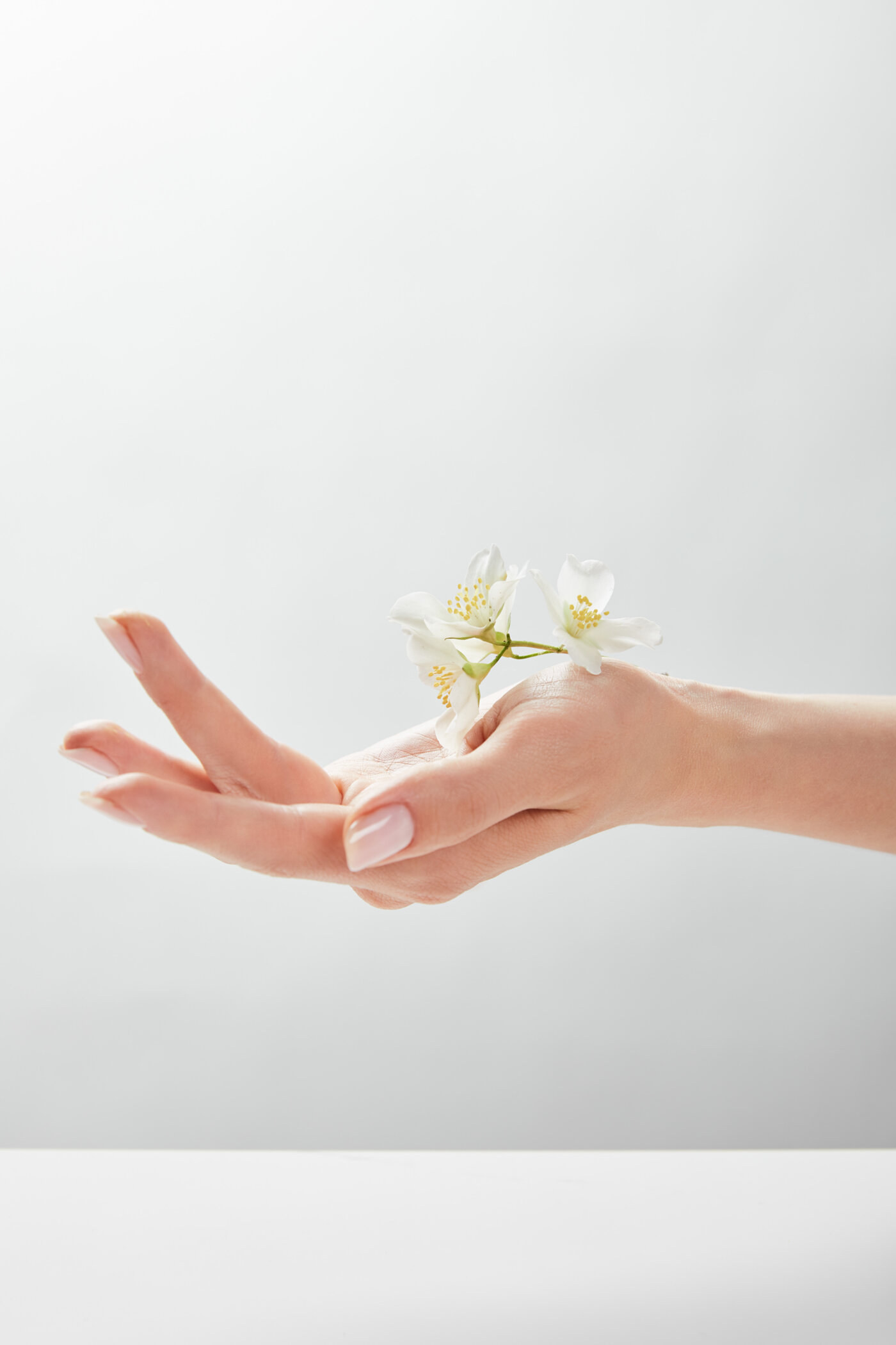 Een vrouwenhand uitgestrekt met witte jasmijn-bloemen — een gebaar van geven.